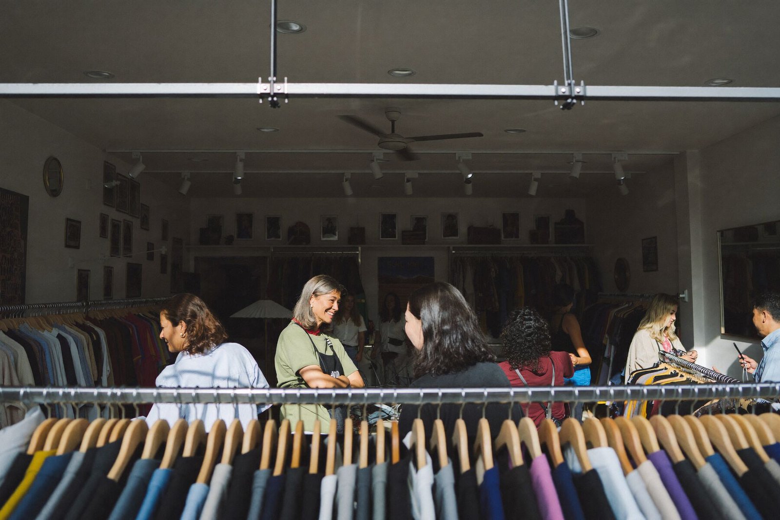 Customers browsing a busy boutique while the owner greets someone at the door