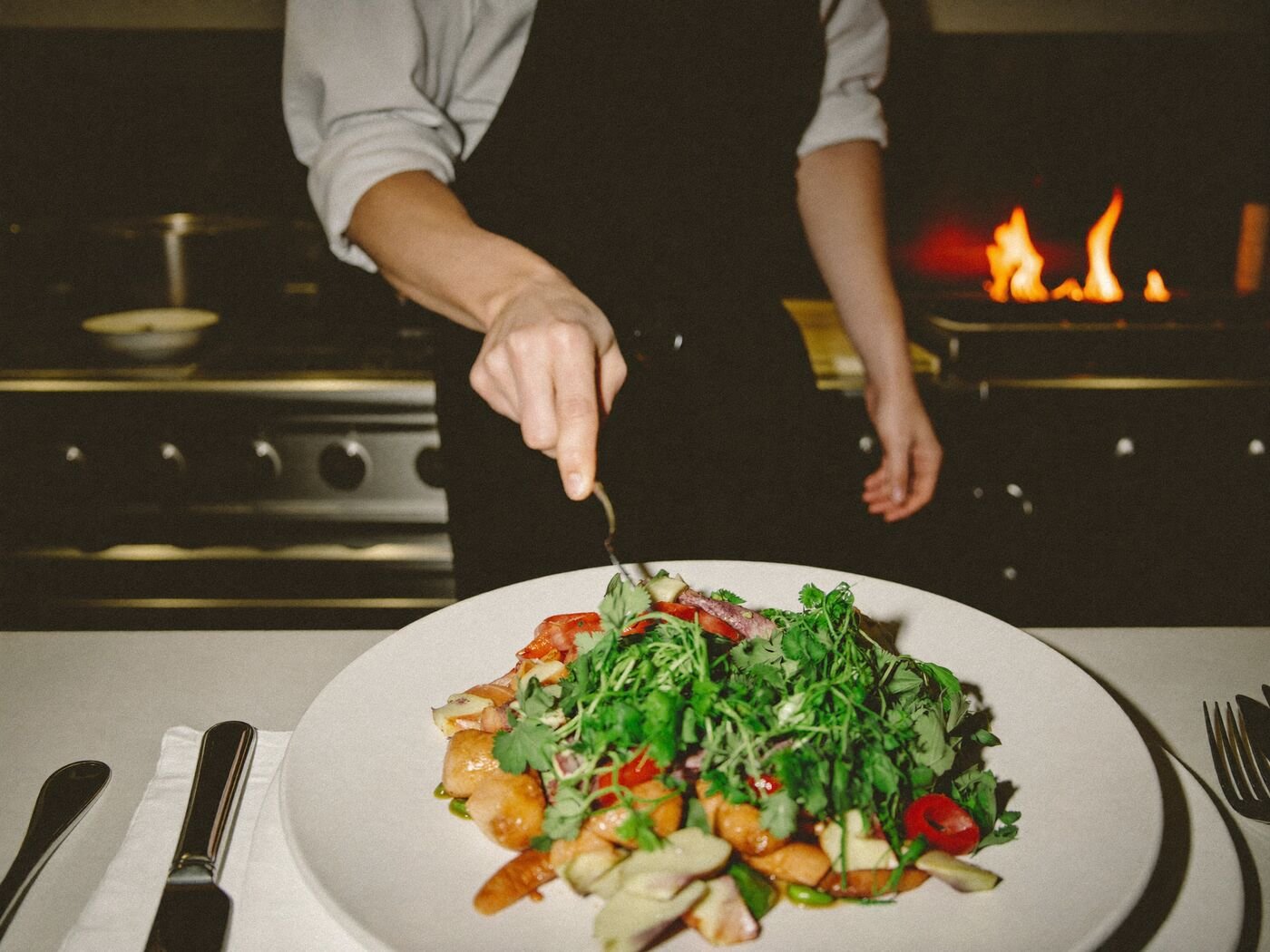 Chef plating a dish in an open kitchen